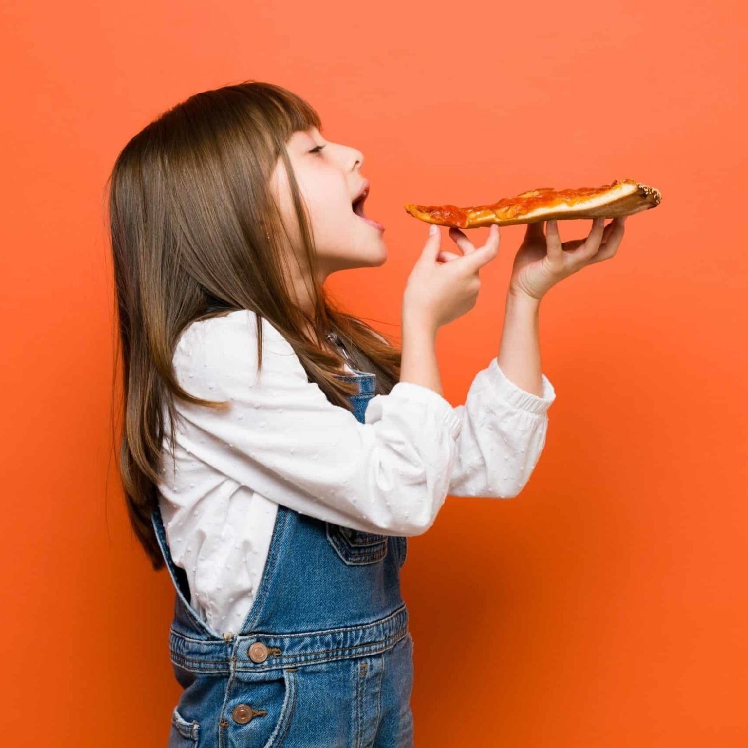 young female student with brown hair enjoying slice of pizza
